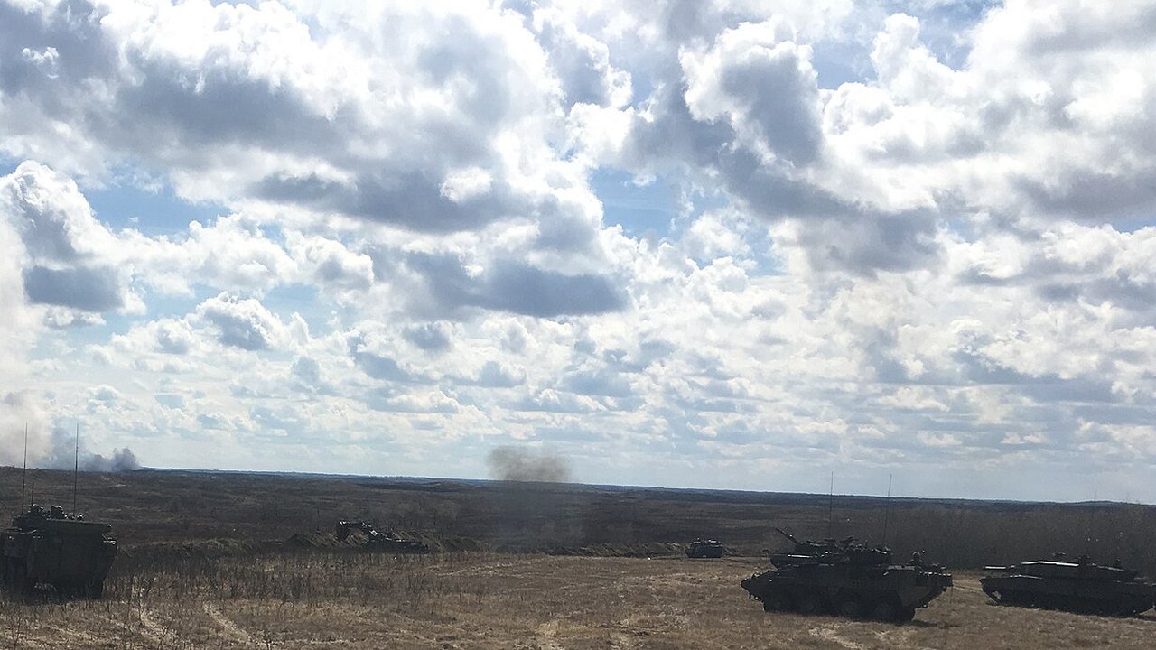 Stand-in, not a photo of this event: April 14, 2019 file photo of armoured vehicles spread across the flat brown prairie of the CFB Wainwright training area under a cloudy sky, with plumes of smoke on the horizon