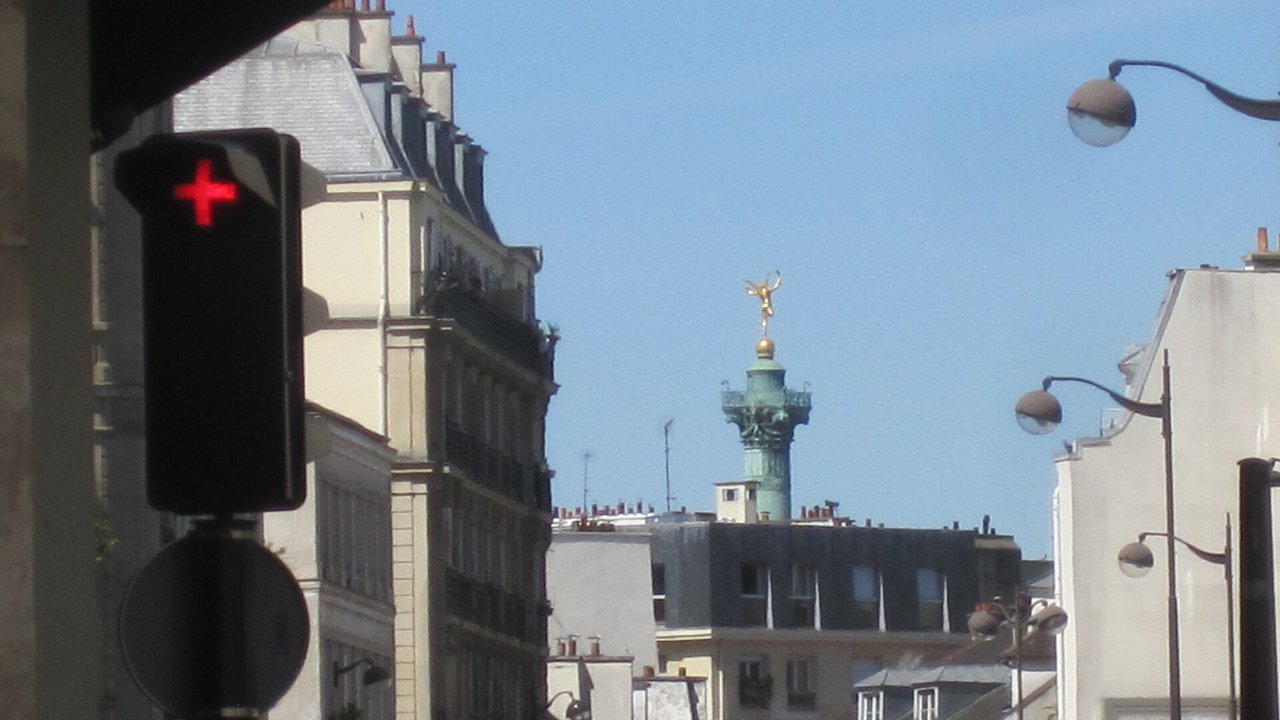 Stand-in, not a photo of this event: a July 2022 file photo of the gilded July Column at Place de la Bastille in Paris rising above rooftops, with a red pedestrian signal in the foreground