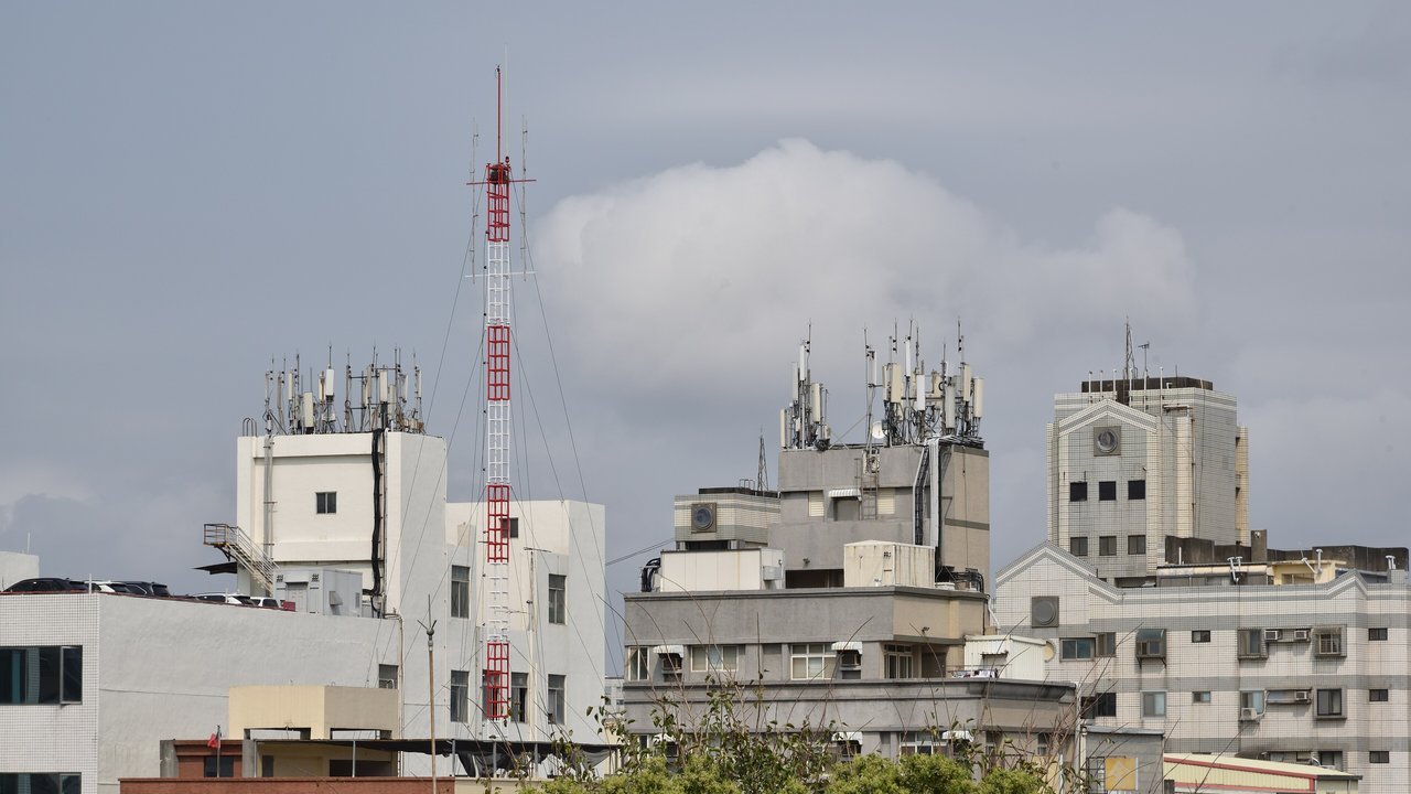 Stand-in, not a photo of this event: a March 2021 file photo of mobile-phone antennas and a red-and-white radio mast on rooftops in Hsinchu, Taiwan, under a cloudy sky
