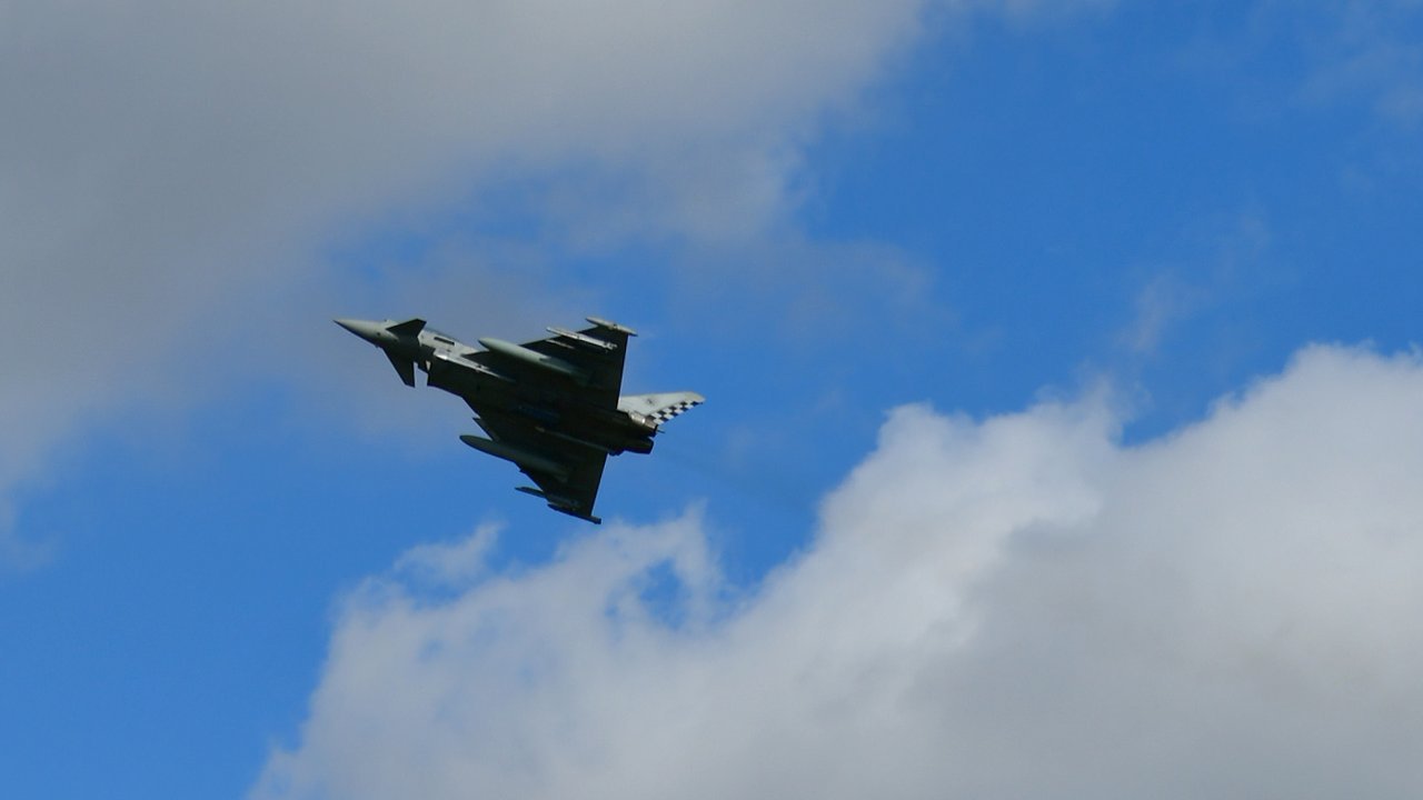 Stand-in, not a photo of this event: August 2023 photo of an Italian Air Force Eurofighter Typhoon flying over Šiauliai Air Base, Lithuania, against blue sky and white clouds