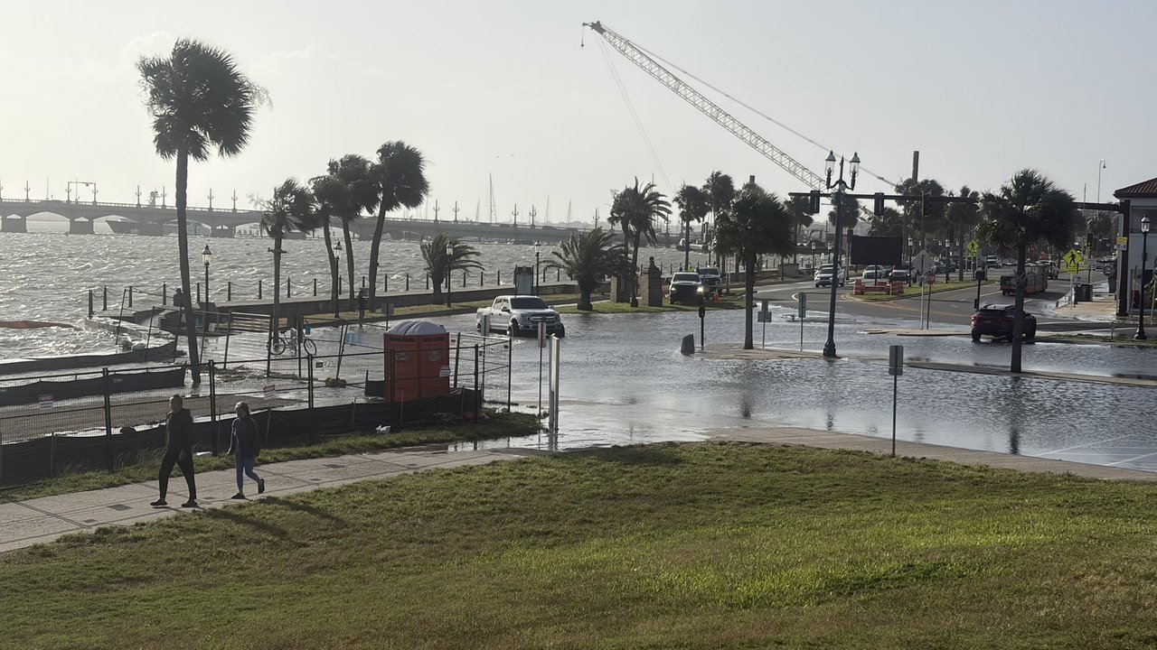 Photo posted on X by @vannschaffner: seawater covers a waterfront street lined with palm trees in St. Augustine, Florida, on Oct. 26, 2026, with parked cars standing in the water, a construction crane overhead and the Bridge of Lions in the distance
