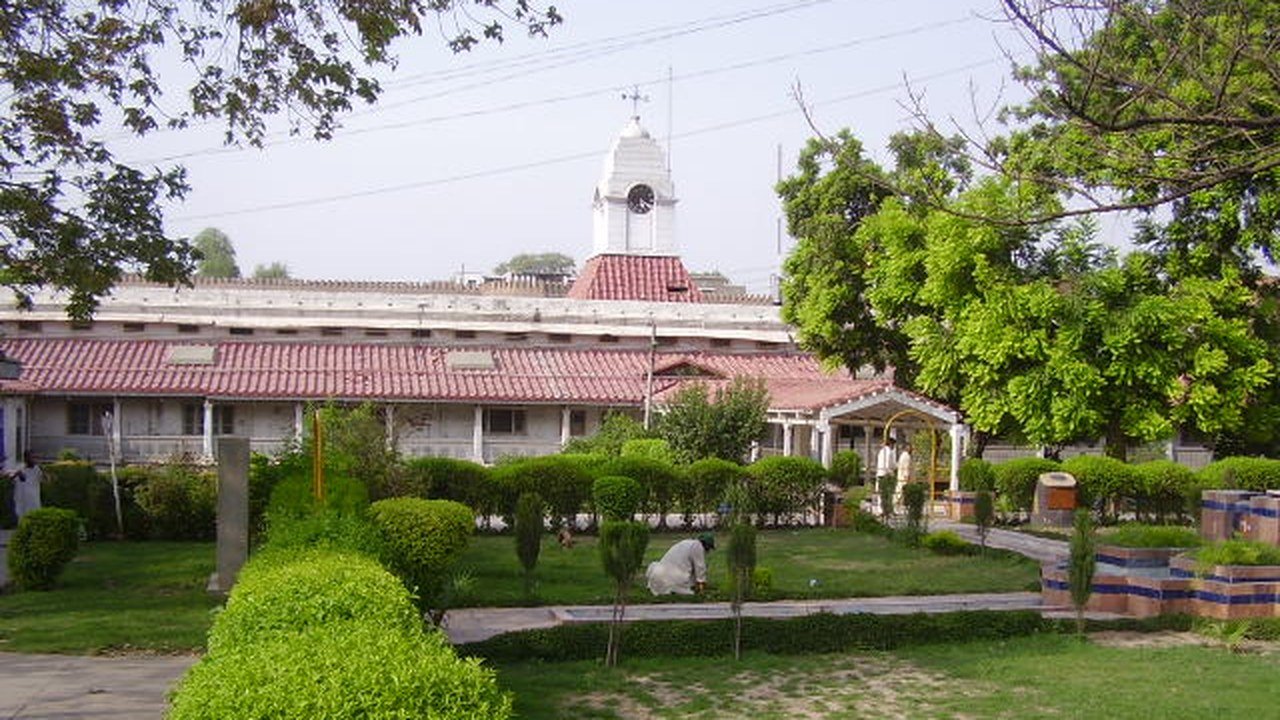 Stand-in, not a photo of this event: the long red-roofed main building of Lady Reading Hospital in Peshawar, topped by a white clock tower, seen across trimmed hedges and a lawn in 2009