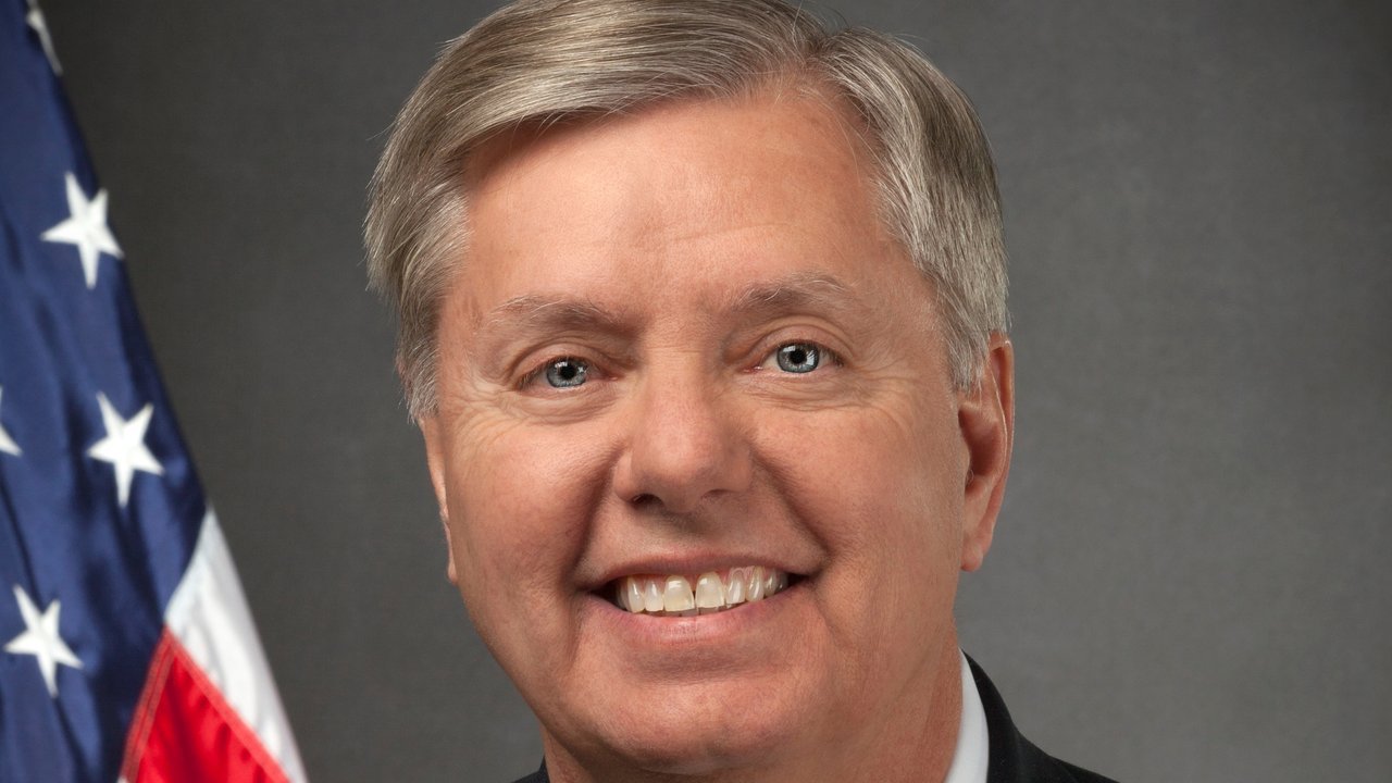 File photo: Sen. Lindsey Graham’s official 2013 Senate portrait, smiling, in a dark suit and red tie in front of a U.S. flag