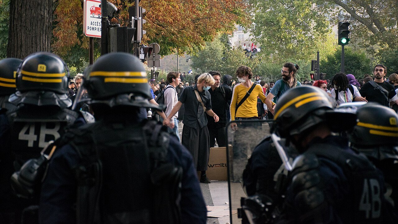 Related photo, not the Lens incident: French riot police in helmets face young protesters near Place de la Nation at the end of the Paris high school and student march on October 6, 2026