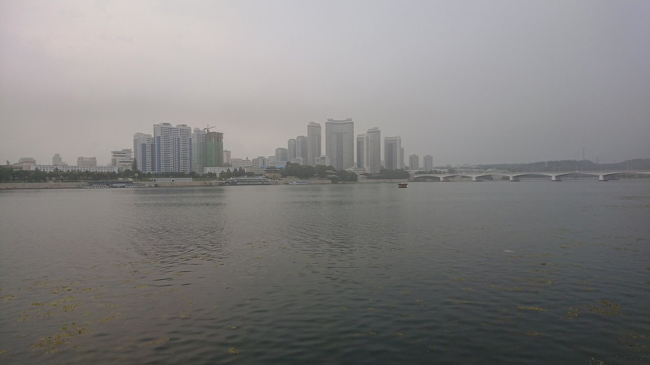 Stand-in, not a photo of this event: a July 2019 file photo of the Pyongyang skyline across the Taedong River on a hazy day, with high-rise apartment towers and a long bridge on the right