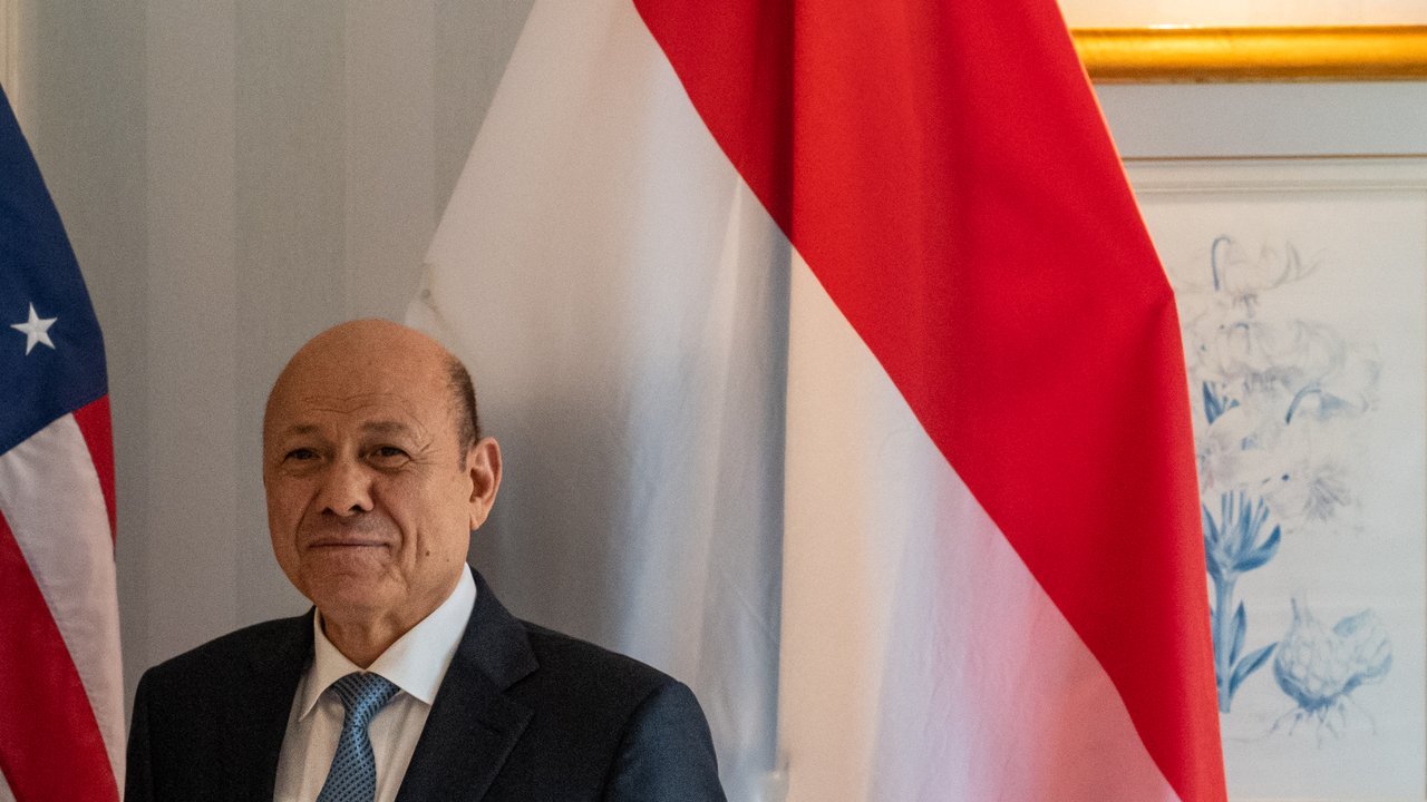 File photo, not from this week: Rashad al-Alimi, head of Yemen’s Presidential Leadership Council, in a dark suit beside a Yemeni flag during a meeting in Munich in February 2023