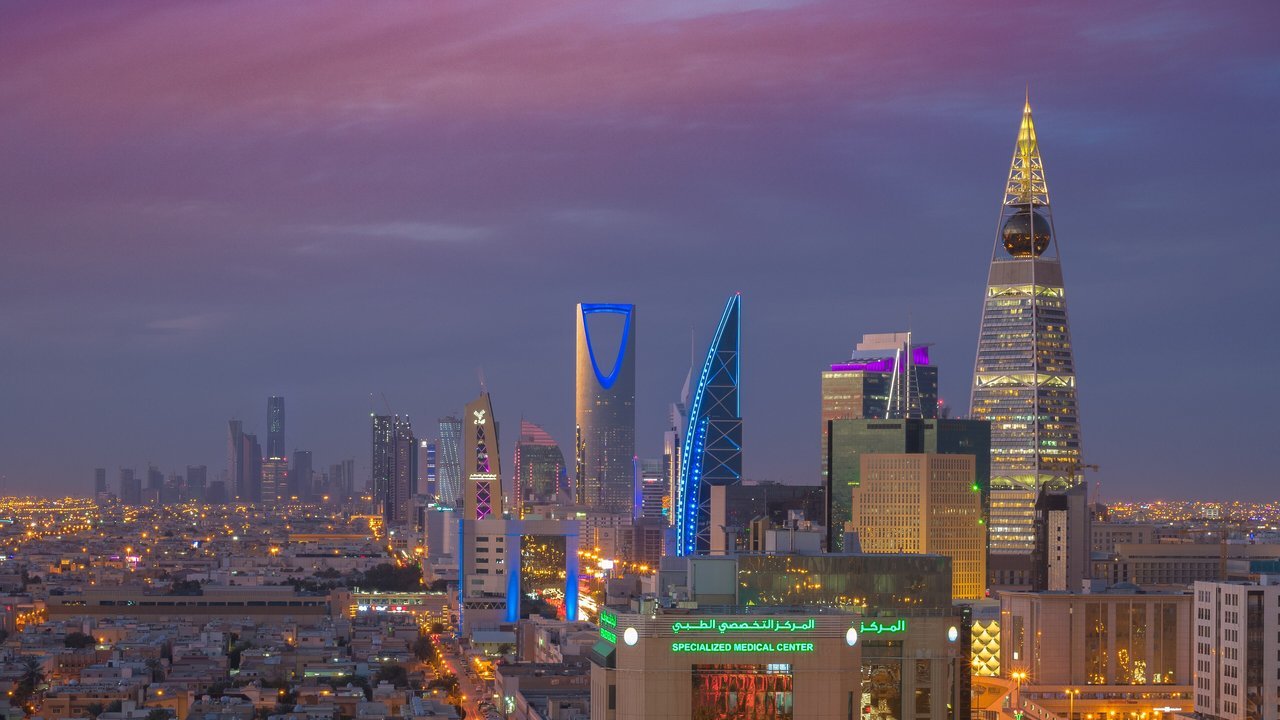 Archival stand-in: Riyadh’s skyline at dusk in February 2018, with the Kingdom Centre and King Abdullah Financial District towers lit against a purple sky