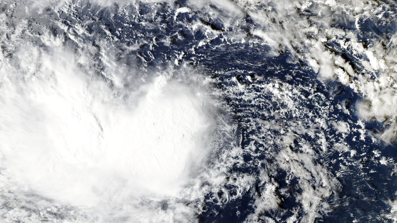 True-color satellite view of Tropical Storm Champi on October 15, 2026, a large, lopsided mass of bright white cloud over blue ocean