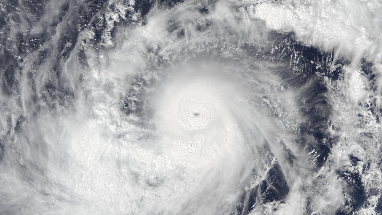 Satellite view of Typhoon Champi east of Guam on October 17, 2026, 1:44 PM ChST, a tight spiral of white cloud bands around a small clear eye over dark ocean, hours before its closest approach