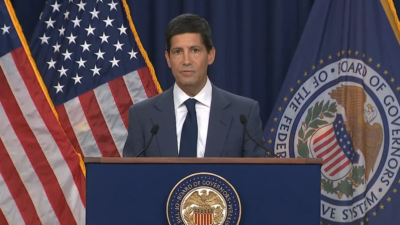 Image posted on X by @_StephanieMyers: Federal Reserve Chair Kevin Warsh stands at a blue lectern bearing the Board of Governors seal, with a U.S. flag behind him on the left and a Federal Reserve Board flag on the right, during his news conference in Washington on Oct. 28, 2026